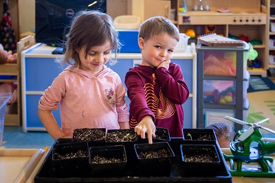 Two children planting seeds together in their Seeds of Learning classroom